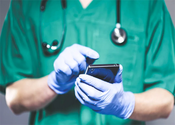 Doctor in surgical gloves holding a smartphone